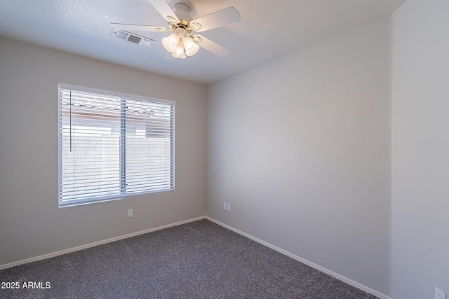 spare room featuring ceiling fan, dark carpet, visible vents, and baseboards