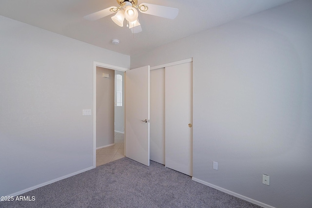 unfurnished bedroom with light carpet, a closet, a ceiling fan, and baseboards