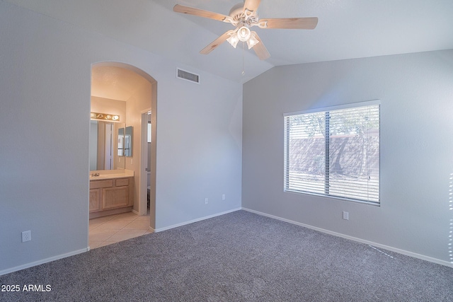 unfurnished bedroom with arched walkways, lofted ceiling, light carpet, visible vents, and baseboards