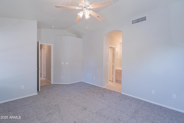 spare room featuring arched walkways, visible vents, light carpet, vaulted ceiling, and ceiling fan