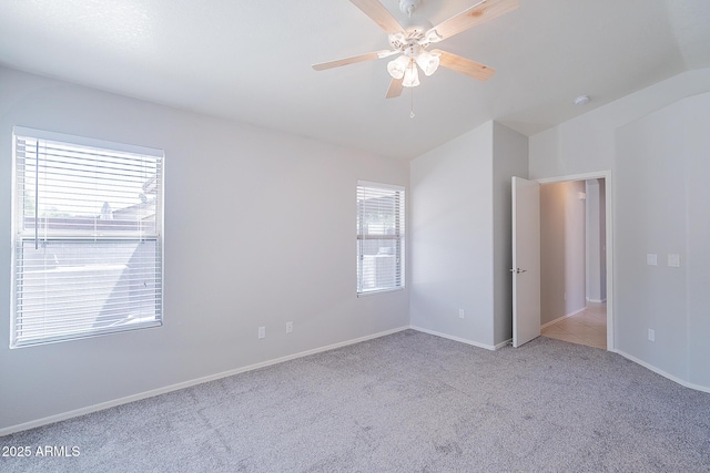 carpeted spare room featuring ceiling fan, baseboards, and vaulted ceiling