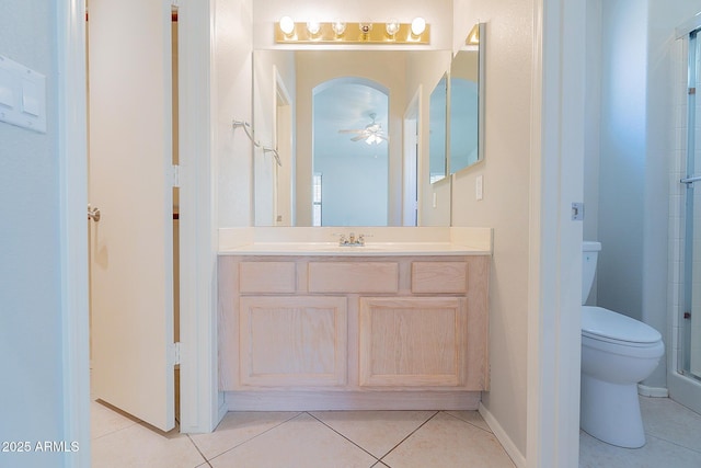 bathroom featuring ceiling fan, tile patterned flooring, a shower with shower door, toilet, and vanity