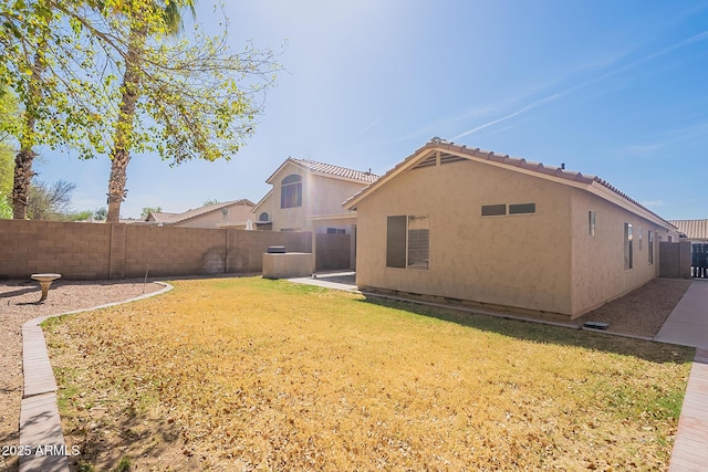 rear view of house with a yard, a fenced backyard, a patio, and stucco siding