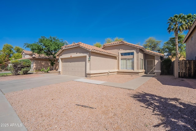 mediterranean / spanish-style home featuring an attached garage, fence, driveway, a tiled roof, and stucco siding