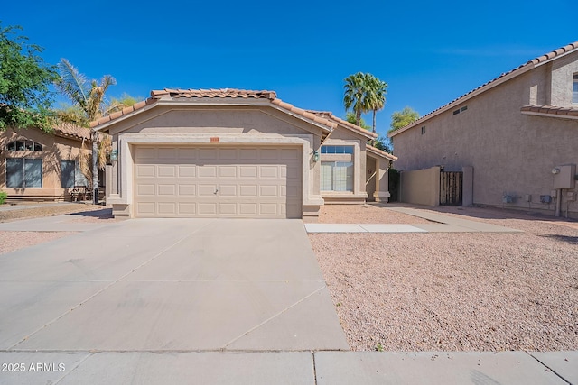 mediterranean / spanish-style house with driveway, a tiled roof, an attached garage, and stucco siding