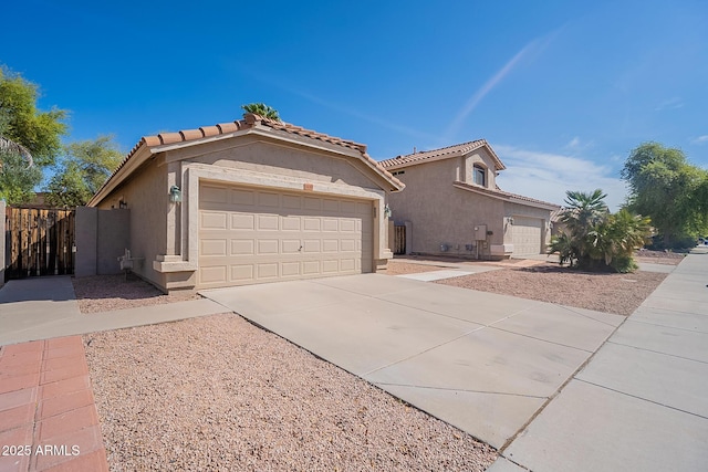 mediterranean / spanish-style house featuring a garage, fence, a tile roof, concrete driveway, and stucco siding