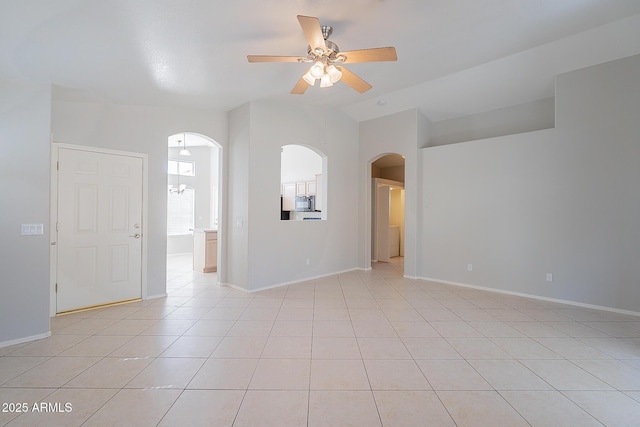 unfurnished room with a ceiling fan, arched walkways, vaulted ceiling, and light tile patterned floors