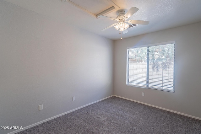 unfurnished room featuring baseboards, visible vents, dark carpet, and ceiling fan