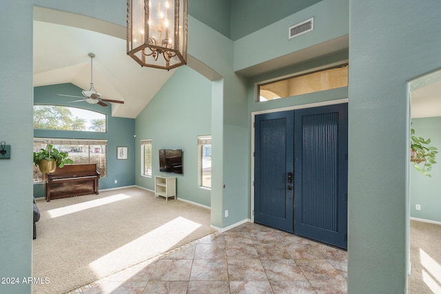 foyer with high vaulted ceiling, light colored carpet, and ceiling fan with notable chandelier