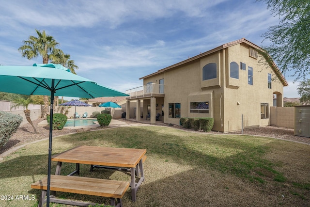 exterior space featuring a yard, a balcony, a patio area, and a fenced in pool