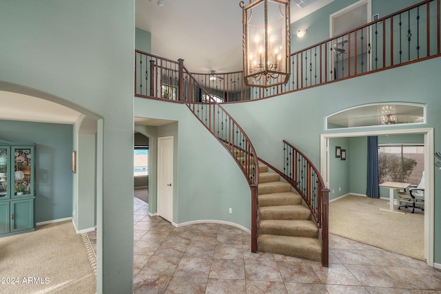 stairway with a high ceiling, carpet floors, and an inviting chandelier