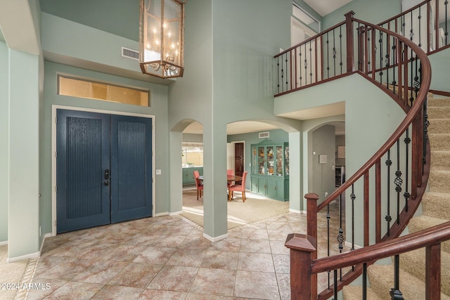 carpeted foyer with a towering ceiling and a notable chandelier