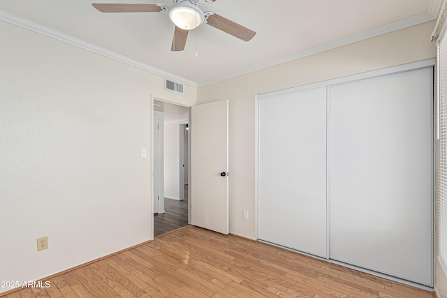 unfurnished bedroom featuring ceiling fan, a closet, ornamental molding, and light hardwood / wood-style flooring