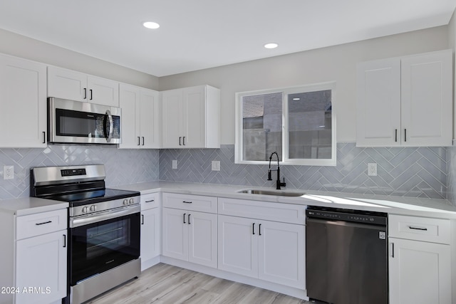 kitchen featuring white cabinetry, sink, light hardwood / wood-style floors, and appliances with stainless steel finishes