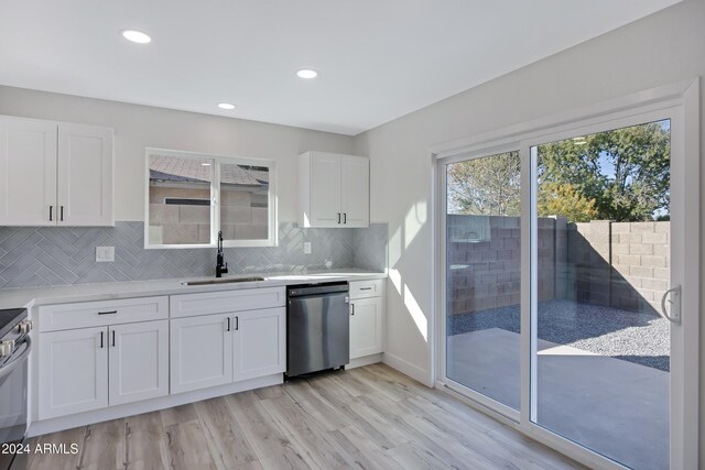 kitchen with white cabinets, light hardwood / wood-style floors, and stainless steel dishwasher