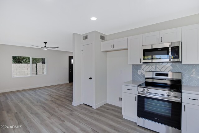 kitchen with decorative backsplash, appliances with stainless steel finishes, light wood-type flooring, ceiling fan, and white cabinets