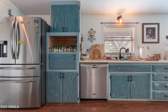 kitchen featuring sink, blue cabinets, dark wood-type flooring, and appliances with stainless steel finishes