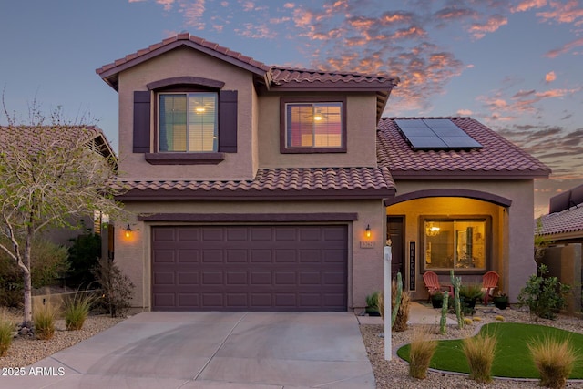 mediterranean / spanish house with stucco siding, a porch, roof mounted solar panels, a garage, and driveway