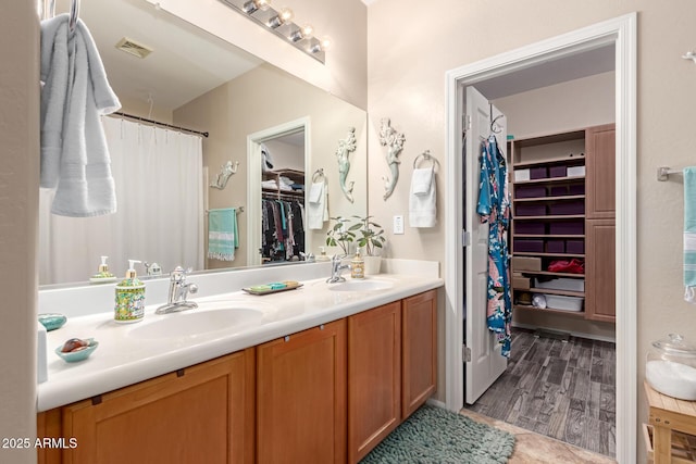 full bath featuring double vanity, a sink, visible vents, and a walk in closet