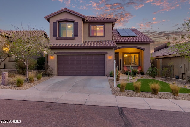 mediterranean / spanish-style home with an attached garage, covered porch, driveway, roof mounted solar panels, and stucco siding