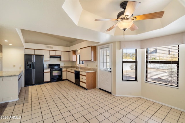 kitchen with sink, black appliances, light tile patterned floors, and a tray ceiling