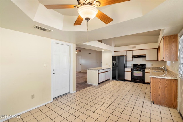 kitchen with ceiling fan, sink, light tile patterned floors, a tray ceiling, and black appliances