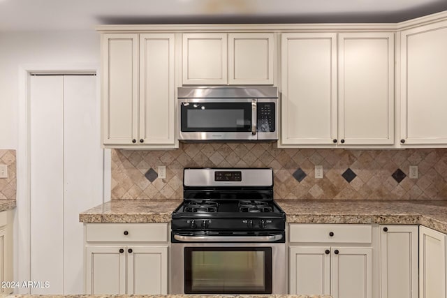 kitchen featuring decorative backsplash, stainless steel appliances, and cream cabinetry