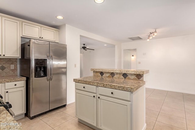 kitchen with stainless steel refrigerator with ice dispenser, ceiling fan, tasteful backsplash, cream cabinetry, and light tile patterned flooring