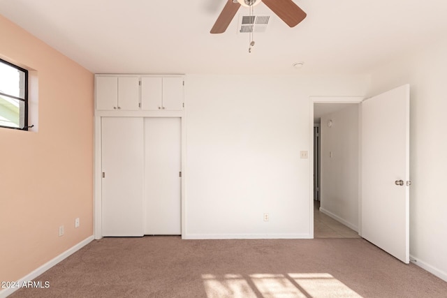 unfurnished bedroom with ceiling fan, light colored carpet, and a closet