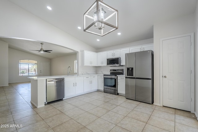 kitchen featuring vaulted ceiling, a sink, a peninsula, stainless steel appliances, and white cabinetry