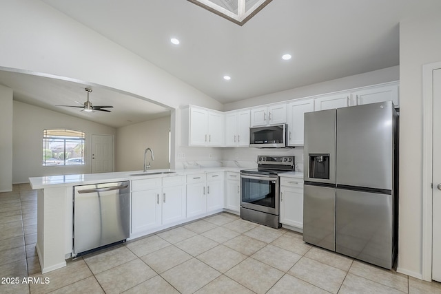 kitchen with a sink, white cabinetry, vaulted ceiling, and stainless steel appliances