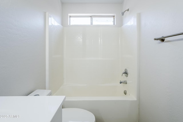bathroom featuring vanity, a textured wall, toilet, and shower / tub combination