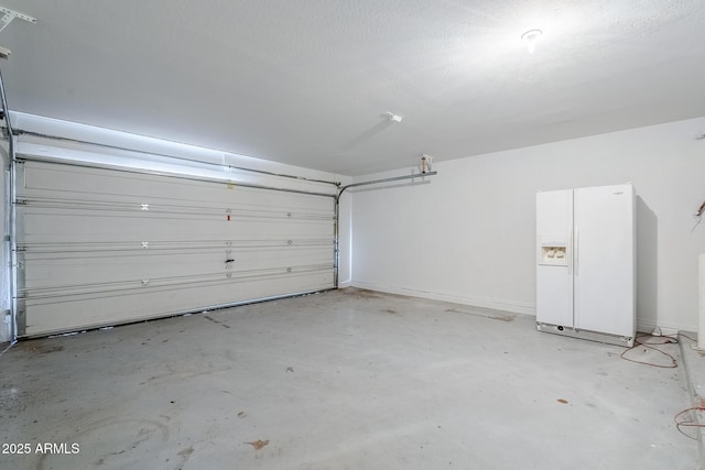 garage with baseboards and white fridge with ice dispenser