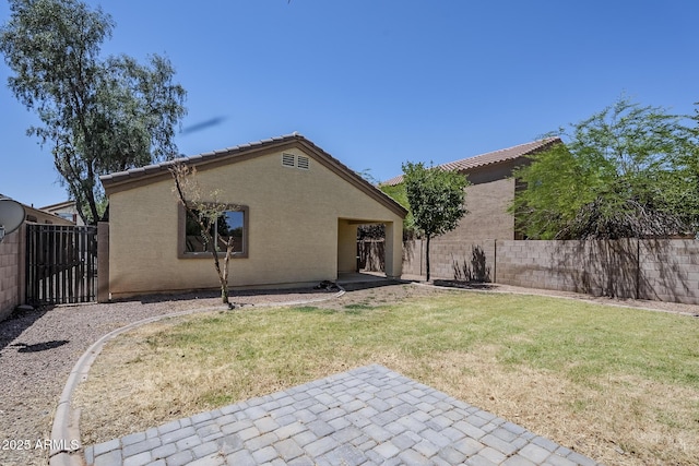 back of house featuring fence, a tile roof, stucco siding, a lawn, and a patio