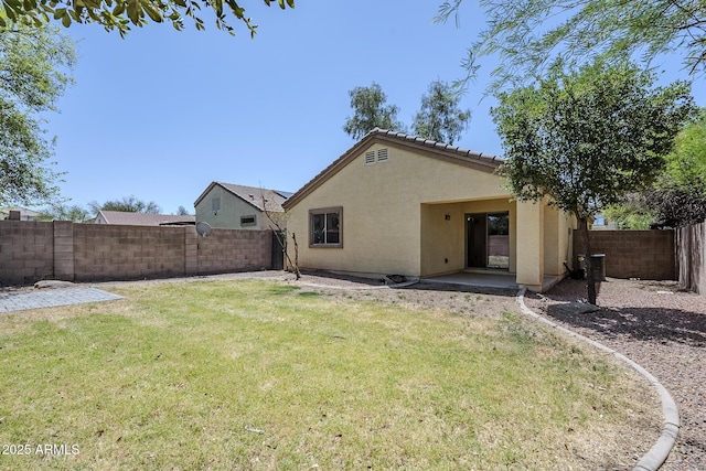 back of property featuring a fenced backyard, a patio area, stucco siding, and a yard