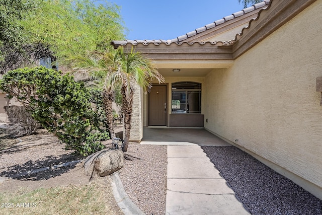 view of exterior entry featuring stucco siding and a tile roof