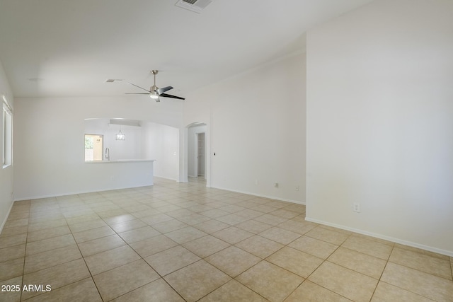 unfurnished room featuring ceiling fan, visible vents, arched walkways, light tile patterned floors, and baseboards