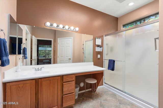 bathroom featuring a shower with shower door and vanity