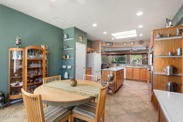 dining area with sink, ceiling fan, and a skylight