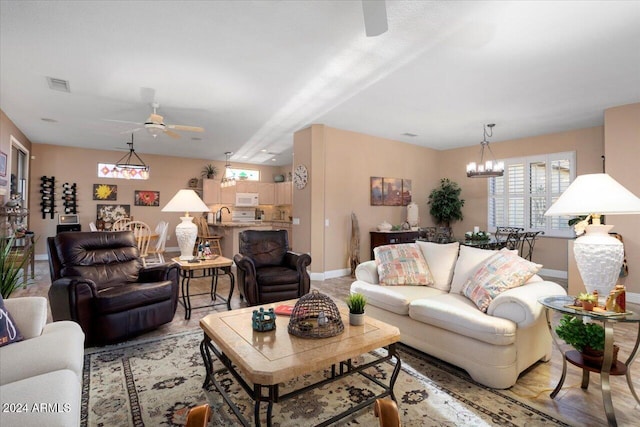 living room with light hardwood / wood-style flooring and ceiling fan with notable chandelier