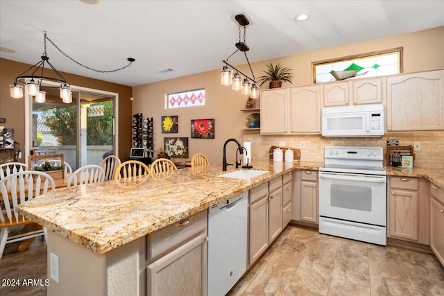 kitchen featuring white appliances, sink, a kitchen bar, kitchen peninsula, and pendant lighting