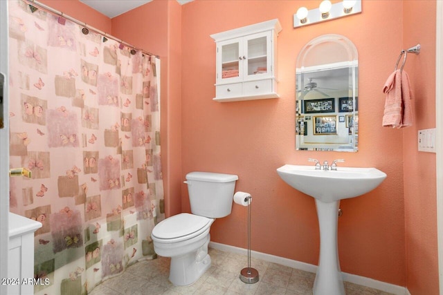 bathroom with toilet, sink, a shower with curtain, and ceiling fan