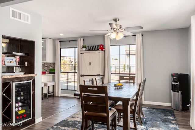 dining space featuring wine cooler, a healthy amount of sunlight, visible vents, and dark wood finished floors