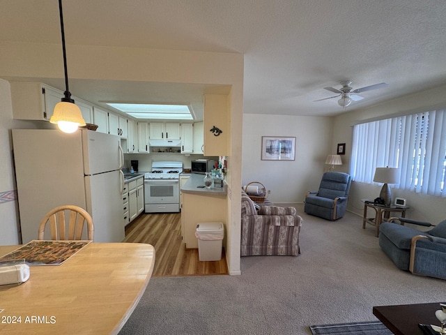 kitchen featuring light colored carpet, pendant lighting, white cabinets, white appliances, and ceiling fan