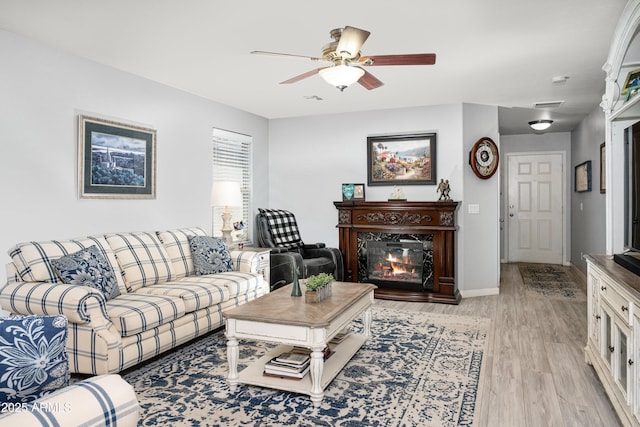 907 E Kelsi Ave, San Tan Valley, AZ 85140 - living area featuring light wood-style floors, a glass covered fireplace, a ceiling fan, and baseboards