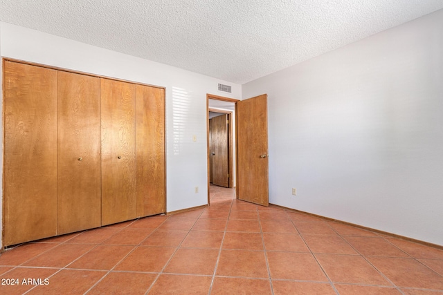 unfurnished bedroom with tile patterned flooring, a closet, and a textured ceiling