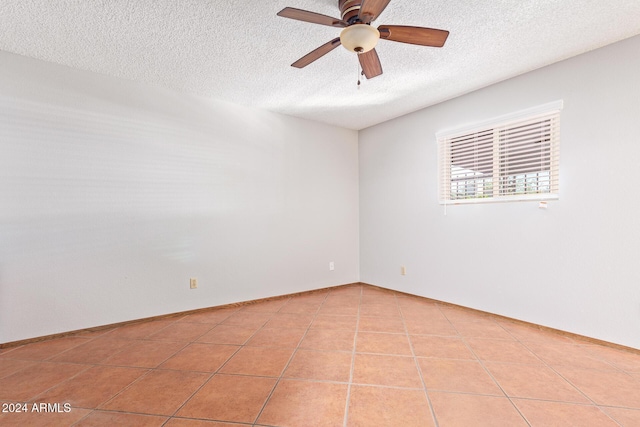 tiled empty room with ceiling fan and a textured ceiling