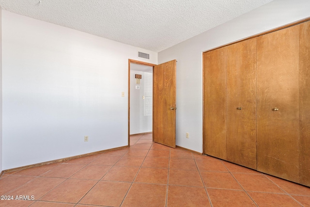 unfurnished bedroom featuring light tile patterned floors, a textured ceiling, and a closet