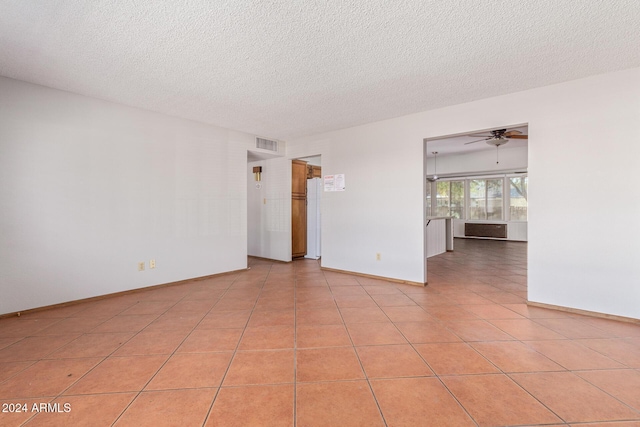 empty room featuring light tile patterned flooring, ceiling fan, and a textured ceiling