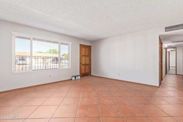 tiled spare room with a textured ceiling